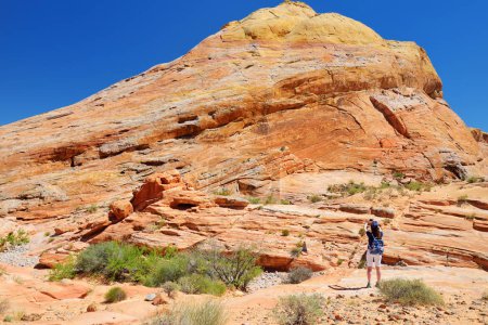 Foto de Young female hiker exploring amazing sandstone formations in Valley of Fire State Park, Nevada, USA. Exploring the American Southwest. - Imagen libre de derechos