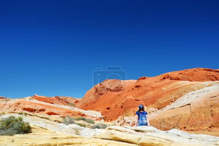 Téléchargez les photos : Young female hiker exploring amazing sandstone formations in Valley of Fire State Park, Nevada, USA. Exploring the American Southwest. - en image libre de droit