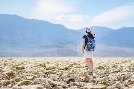 Photo for Young female tourist exploring famous salt formations at Devils Golf Course in Death Valley National Park, California, USA. Exploring the American Southwest. - Royalty Free Image