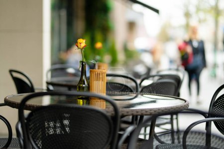 Foto de Mesa de restaurante al aire libre bellamente decorada con flor de rosa en una botella en Vilna, Lituania, en un bonito día de verano. Comer al aire libre. - Imagen libre de derechos