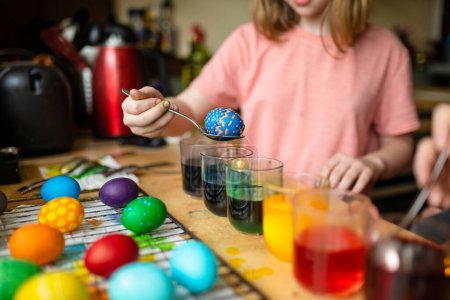 Téléchargez les photos : Jolie fille preteen teindre des œufs de Pâques à la maison. Enfant peignant des œufs colorés pour la chasse de Pâques. Le gamin se prépare pour Pâques. Traditions familiales. - en image libre de droit
