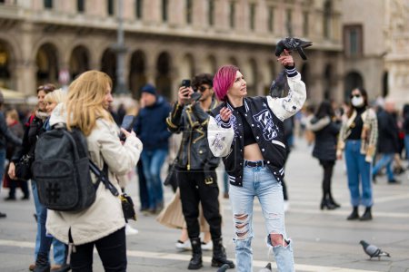 Téléchargez les photos : MILAN, ITALIE - AVRIL 2022 : Un groupe de personnes nourrit les pigeons sur la place de la Cathédrale ou Piazza del Duomo dans le centre de Milan, Lombardie, Italie. - en image libre de droit