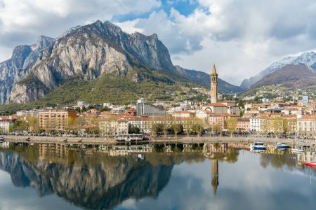 Sunny aerial cityscape of Lecco town on spring day. Picturesque waterfront of Lecco town located between famous Lake Como and scenic Bergamo Alps mountains. Vacation destination in Italy.