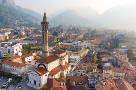 Photo for Foggy aerial sunrise cityscape of Lecco town on spring day. Picturesque waterfront of Lecco town located between famous Lake Como and scenic Bergamo Alps mountains. Vacation destination in Italy. - Royalty Free Image