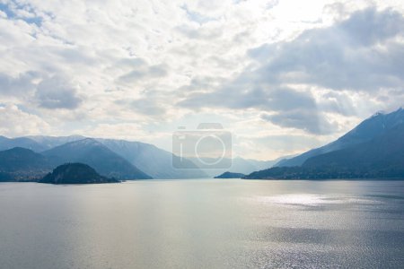 Foto de Hermosa vista aérea del famoso Lago Como en el soleado día de verano. Nubes que se reflejan en aguas tranquilas del lago con montañas de los Alpes en el fondo. Lombardía, Italia. - Imagen libre de derechos