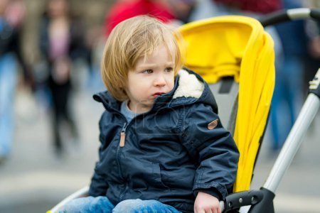 Photo for Sweet toddler boy sitting in a stroller outdoors. Little child in pram. Infant kid in pushchair. City walks with kids. Family leisure with little child. - Royalty Free Image