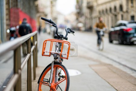 Foto de Bicicleta naranja estacionada en la calle de Milán. Explorando un centro de la ciudad. Milán, Lombardía, Italia. - Imagen libre de derechos