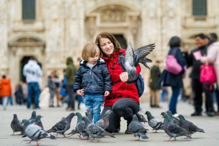 Téléchargez les photos : Jeune mère et son fils nourrissant les pigeons sur la place de la Cathédrale ou Piazza del Duomo dans le centre de Milan, Lombardie, Italie. - en image libre de droit
