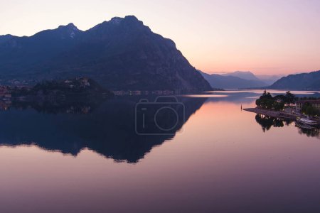 Téléchargez les photos : Belle vue aérienne du célèbre lac de Côme sur le coucher de soleil violet. Montagnes se reflétant dans les eaux calmes du lac avec chaîne de montagnes alpines sur le fond. Lombardie, Italie. - en image libre de droit
