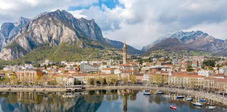 Sunny aerial cityscape of Lecco town on spring day. Picturesque waterfront of Lecco town located between famous Lake Como and scenic Bergamo Alps mountains. Vacation destination in Italy.