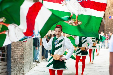 Foto de SIENA, ITALIA - JULIO 2013: Miembros de la noble Contrada dell 'Oca portando banderas con un ganso coronado en el Corteo Storico, un histórico desfile de disfraces en Siena, Toscana, Italia. - Imagen libre de derechos