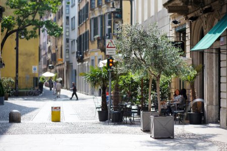 Téléchargez les photos : MILAN, ITALIE - MAI 2011 : Touristes et habitants assis dans un café extérieur dans une rue animée du centre de Milan, une métropole du nord de la Lombardie italienne. Milan, Lombardie, Italie. - en image libre de droit