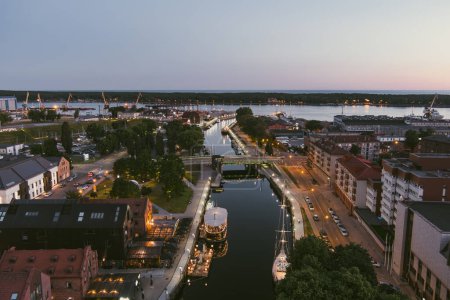 Foto de Vista aérea panorámica del casco antiguo de Klaipeda, Lituania a la luz de la noche. Zona portuaria de la ciudad de Klaipeda y sus alrededores en la noche de verano. - Imagen libre de derechos