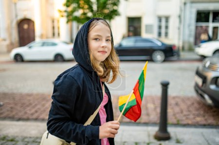 Téléchargez les photos : Jolie jeune fille tenant le drapeau tricolore lituanien le jour de la fête nationale lituanienne. Enfant célébrant la fête nationale. - en image libre de droit