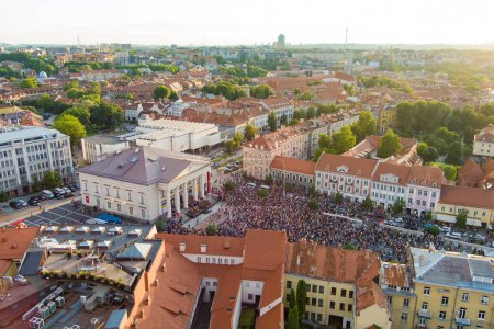 Téléchargez les photos : Vue aérienne des foules qui célèbrent la Journée de l'Etat lituanien. Beaucoup de gens chantent l'hymne national de Lituanie sur la place de l'hôtel de ville. - en image libre de droit