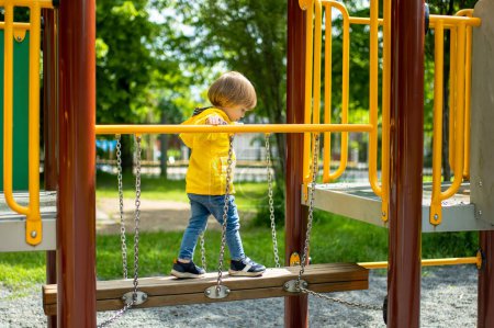Photo for Cute toddler boy having fun on a playground outdoors on warm summer day. Active leisure for kids in summer. - Royalty Free Image