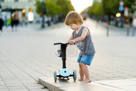 Téléchargez les photos : Petit garçon drôle chevauchant un scooter bébé à l'extérieur le jour de l'été. Équilibre d'entraînement enfant sur mini vélo. Activités estivales pour les petits enfants. - en image libre de droit