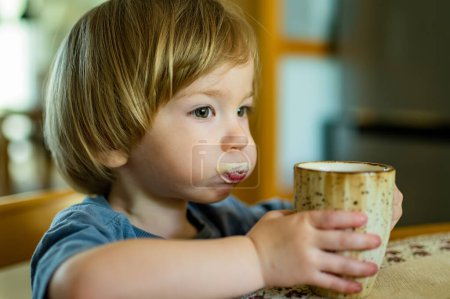 Foto de Lindo niño bebiendo café descafeinado en casa. Niño pequeño bebiendo bebidas calientes en el interior. Bebidas para niños. - Imagen libre de derechos