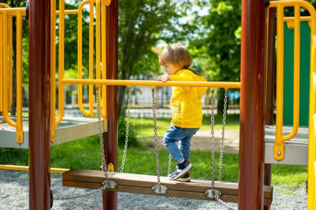 Photo for Cute toddler boy having fun on a playground outdoors on warm summer day. Active leisure for kids in summer. - Royalty Free Image