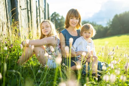 Photo for Two big sisters and their toddler brother having fun outdoors. Two young girls holding baby boy on summer day. Children with large age gap. Big age difference between siblings. Big family. - Royalty Free Image