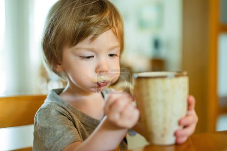 Photo for Cute toddler boy drinking decaffeinated coffee at home. Small child drinking hot beverage indoors. Beverages for kid. - Royalty Free Image