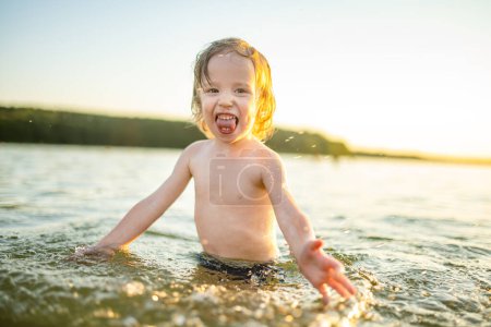 Photo for Cute toddler boy playing by a lake on hot summer day. Adorable child having fun outdoors during summer vacations. Water activities for kids. - Royalty Free Image