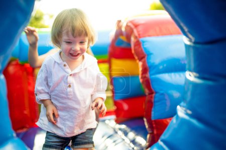 Photo for Cute toddler boy jumping on a inflatable bouncer in a backyard on warm and sunny summer day. Sports and exercises for children. Summer outdoor leisure activities. - Royalty Free Image