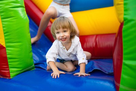 Photo for Cute toddler boy jumping on a inflatable bouncer in a backyard on warm and sunny summer day. Sports and exercises for children. Summer outdoor leisure activities. - Royalty Free Image