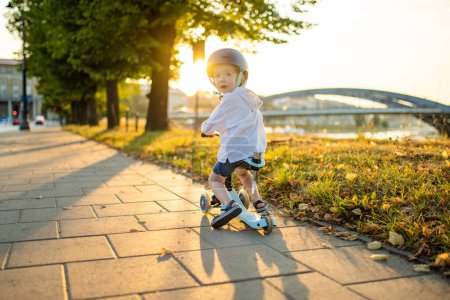 Téléchargez les photos : Petit garçon drôle chevauchant un scooter bébé à l'extérieur le jour de l'été. Équilibre d'entraînement enfant sur mini vélo. Activités estivales pour les petits enfants. - en image libre de droit