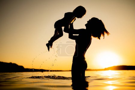 Photo for Cute toddler boy and his teenage sister playing by a lake on hot summer day. Adorable child having fun outdoors during summer vacations. Water activities for kids. - Royalty Free Image