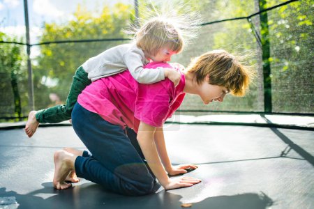 Photo for Cute toddler boy and his sister jumping on a trampoline in a backyard. Sports and exercises for children. Summer outdoor leisure activities. - Royalty Free Image
