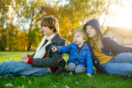Photo for Two big sisters and their toddler brother having fun outdoors. Two young girls with a toddler boy on autumn day. Children with large age gap. Big age difference between siblings. Big family. - Royalty Free Image