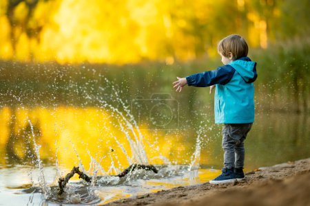 Foto de Adorable niño divirtiéndose junto al lago Gela en el soleado día de otoño. Niño explorando la naturaleza en el día de otoño en Vilna, Lituania. Actividades divertidas de otoño para niños. - Imagen libre de derechos