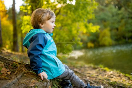 Téléchargez les photos : Adorable tout-petit garçon qui s'amuse au bord du lac Gela le jour d'automne ensoleillé. Enfant explorant la nature le jour d'automne à Vilnius, Lituanie. Activités d'automne amusantes pour les enfants. - en image libre de droit