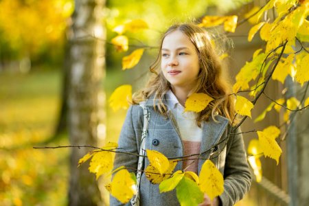 Téléchargez les photos : Adorable jeune fille qui s'amuse le beau jour d'automne. Heureux portrait d'adolescent dans le parc d'automne. Activités d'automne pour les enfants. - en image libre de droit