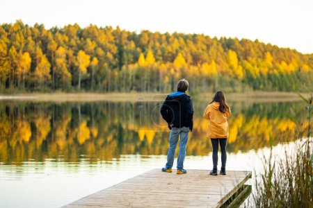 Foto de Hermosa pareja divirtiéndose junto al lago Gela en el soleado día de otoño. Personas explorando la naturaleza en el día de otoño en Vilna, Lituania. Actividades divertidas de otoño. - Imagen libre de derechos