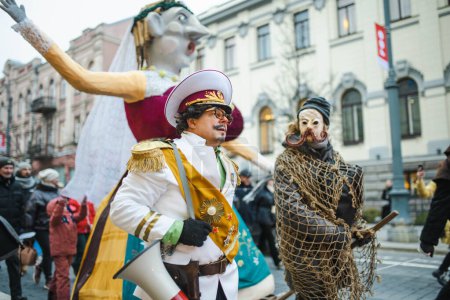 Foto de VILNIUS, LITUANIA - 21 DE FEBRERO DE 2023: Cientos de personas celebran Uzgavenes, un festival folclórico anual lituano que tiene lugar antes de Pascua. Participantes con máscaras y disfraces tradicionales. - Imagen libre de derechos