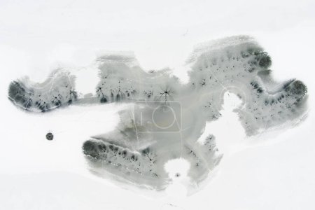 Téléchargez les photos : Vue aérienne du haut vers le bas de la surface gelée du lac en hiver, texture de la glace avec fissures, taches des cours d'eau sous-marins. Paysage hivernal pittoresque. - en image libre de droit