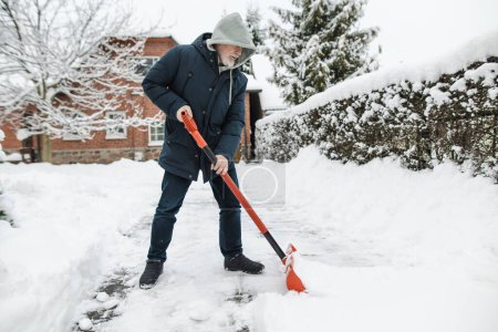 Photo for Mature man shoveling snow in a backyard on winter day. Winter chores. - Royalty Free Image