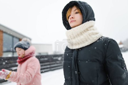 Téléchargez les photos : Funny teen sisters having fun on a walk in snow covered pine forest on chilly winter day. Les adolescentes explorent la nature. Activités hivernales pour les enfants. - en image libre de droit