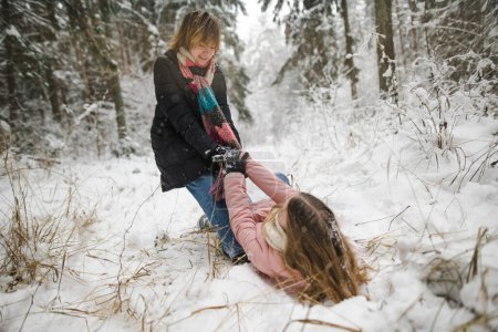 Foto de Divertidas hermanas adolescentes divirtiéndose en un paseo por el bosque de pinos cubierto de nieve en el frío día de invierno. Adolescentes explorando la naturaleza. Actividades de invierno para niños. - Imagen libre de derechos