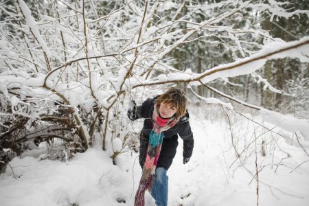 Foto de Linda chica adolescente divirtiéndose en un paseo por el bosque de pinos cubierto de nieve en el frío día de invierno. Niño adolescente explorando la naturaleza. Actividades de invierno para niños. - Imagen libre de derechos