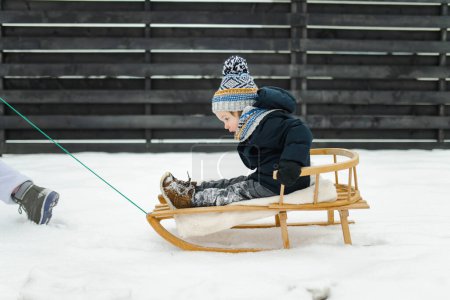 Photo for Funny toddler boy having fun with a sleigh in beautiful winter park. Cute child playing in a snow. Winter activities for kids. - Royalty Free Image