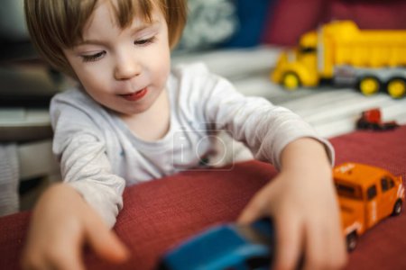 Photo for Cute toddler boy playing with toy cars. Small child having fun with toys. Kid spending time in a cozy living room at home. Family leisure indoors. - Royalty Free Image