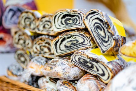Photo for Simtalapis, traditional Lithuanian cake made of yeast dough and poppy seeds, for sale at outdoor farmers market in Vilnius. Traditional spring fair in Vilnius, the capital of Lithuania. - Royalty Free Image