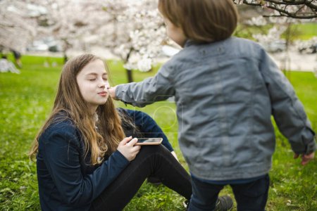 Téléchargez les photos : Jolie adolescente et son petit frère s'amusent à fleurir jardin de cerisiers sur belle journée de printemps. Enfants explorant la nature. Grande différence d'âge entre frères et sœurs. - en image libre de droit