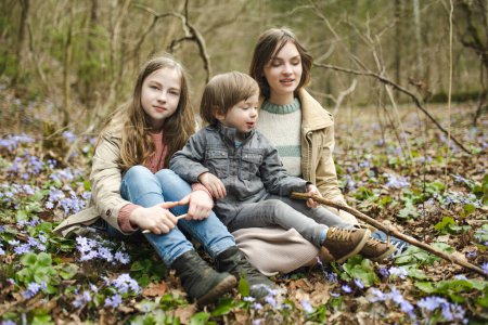 Téléchargez les photos : Deux sœurs et leur petit frère s'amusent lors d'une randonnée dans les bois lors d'une belle journée de printemps ensoleillée. Loisirs familiaux actifs avec enfants. Enfants explorant la nature. - en image libre de droit