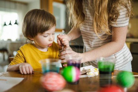 Photo for Big sister and her little brother dyeing Easter eggs at home. Children painting colorful eggs for Easter hunt. Kids getting ready for Easter celebration. Family traditions. - Royalty Free Image