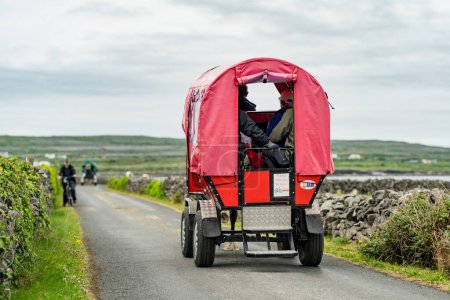 Foto de INISHMORE, IRLANDA - 21 MAY, 2023: Turistas haciendo un recorrido a caballo y en carruaje por la famosa isla de Inishmore, la más grande de las Islas Aran en Galway Bay, Irlanda. - Imagen libre de derechos
