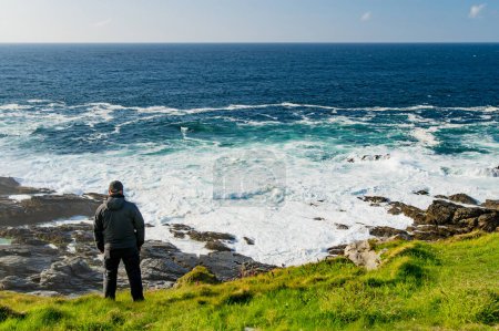 Foto de Turista admirando la belleza escénica de Malin Head, el punto más septentrional de Irlanda, Wild Atlantic Way, espectacular ruta costera. Maravillas de la naturaleza. Numerosos puntos de descubrimiento. Co. Donegal - Imagen libre de derechos
